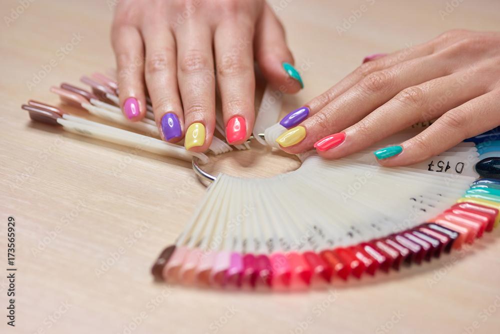 Multicolored summer manicure on female hands. Beautiful pastel manicure on young womans hands, palettes with nail polishes. Salon beauty and spa. Multicolored summer manicure on female hands. Beautiful pastel manicure on young womans hands, palettes with nail polishes. Salon beauty and spa.