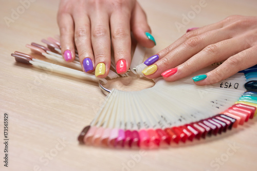 Multicolored summer manicure on female hands. Beautiful pastel manicure on young womans hands  palettes with nail polishes. Salon beauty and spa.