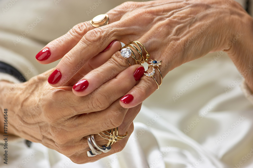 Female hands with golden rings. Senior woman hands with beautiful red nails  wearing a lot of golden rings. Womens wealth and beauty. Stock Photo |  Adobe Stock