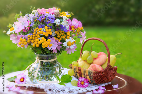 Fotografie Bouquet colorful wild flowers and fruit basket.