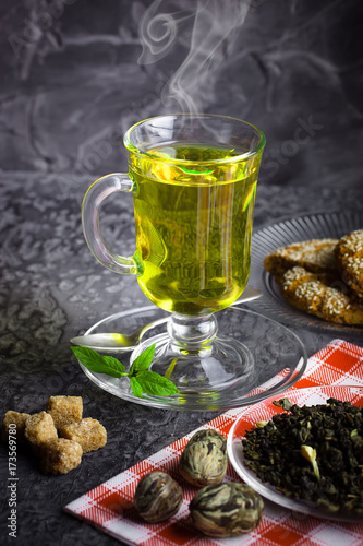 Tea in a cup on a metallic background in a composition with a cookware