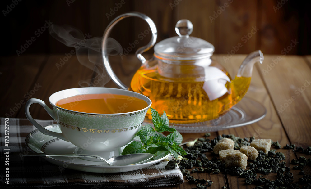 Tea in a cup on a metallic background in a composition with a cookware Tea in a cup on a metallic background in a composition with a cookware