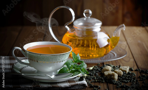 Tea in a cup on a metallic background in a composition with a cookware