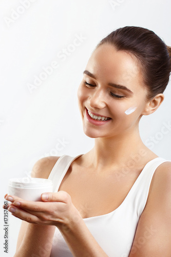 Skincare. Beauty Concept. Young pretty woman holding cosmetic cream and smiling.