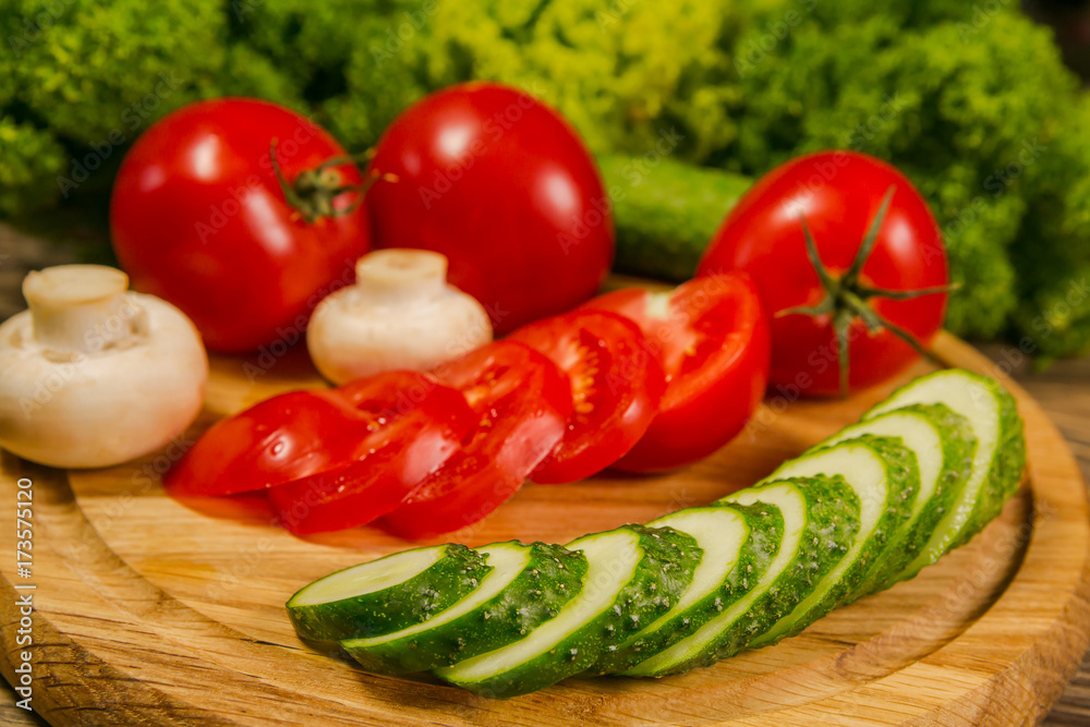 Fresh vegetables. Tomatoes, cucumbers and mushrooms on a wooden board. Delicious vegetarian food. Salad. Fresh vegetables. Tomatoes, cucumbers and mushrooms on a wooden board. Delicious vegetarian food. Salad.