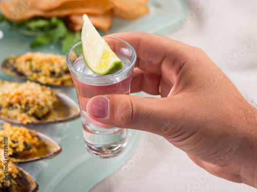 Male hand holding Cocktail. Vodka, gin, tequila with lime photo