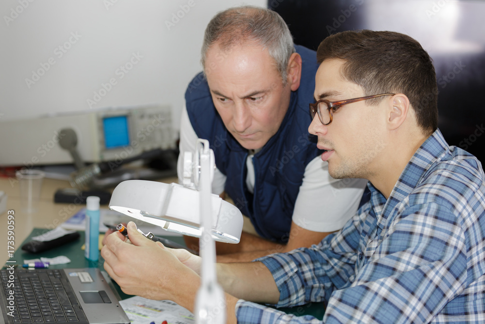 two men repairing electronic device two men repairing electronic device
