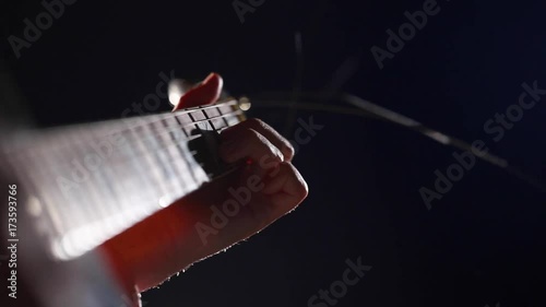 The hand of the musician on the guitar fretboard over closeup photo