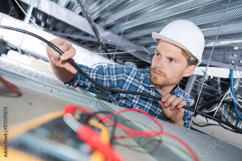 man repairing electrical wiring on the ceiling