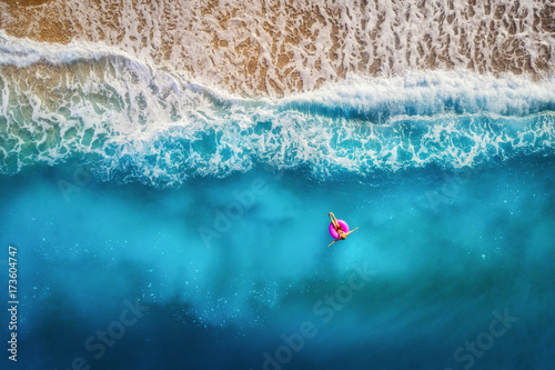 Fotografia Aerial view of slim woman swimming on the pink swim ring in the transparent turquoise sea in Oludeniz,Turkey