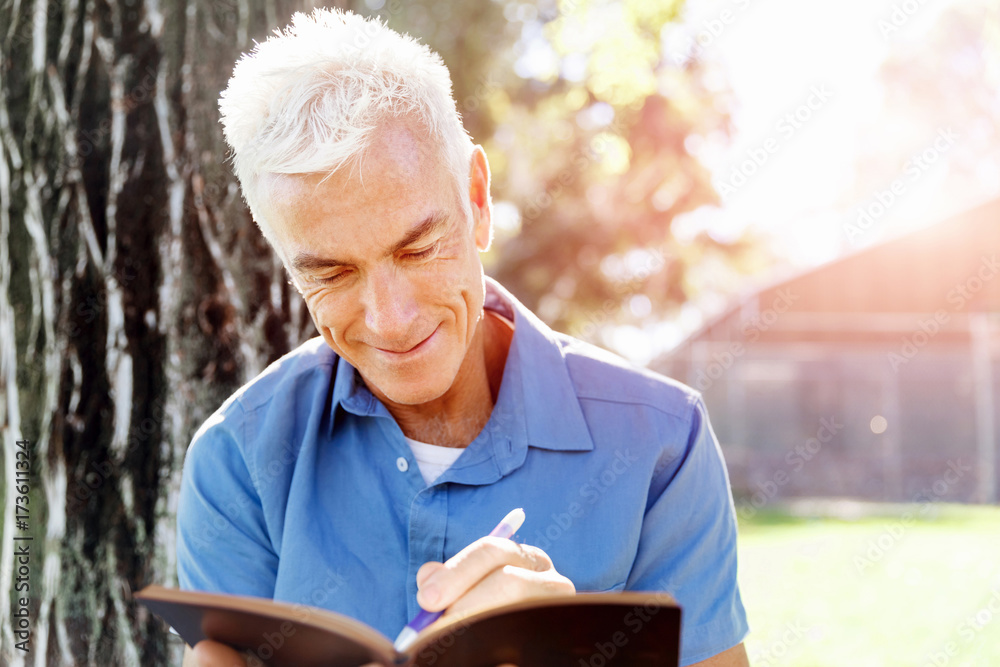 Senior man sittingin park while reading book Senior man sittingin park while reading book