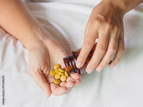 Close up young woman pours the pills out of the bottle. Medicine and health care concept.