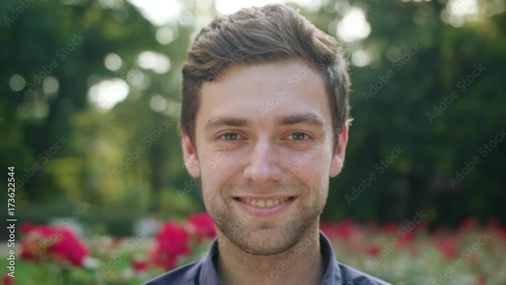 Man's face smiling at the camera in the park. Close-up shoot Man's face smiling at the camera in the park. Close-up shoot