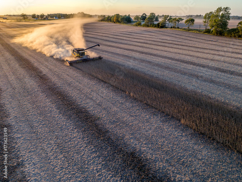 An aerial photo of a large combine leaving a dust trail behind during the fall soybean harvest in Indiana, USA