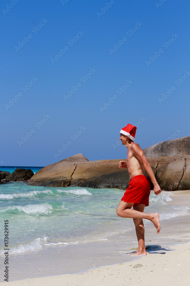 Christmas yoga man in red trousers and Christmas hat on the beach near the ocean. Similan Islands Christmas yoga man in red trousers and Christmas hat on the beach near the ocean. Similan Islands