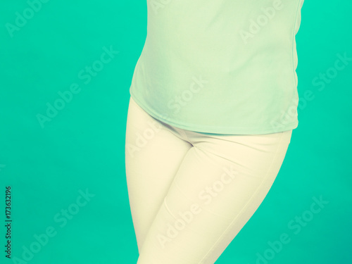 Woman hips, azure blouse shirt and white trousers