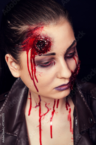 Girl with wounds on her face, bloody stains, makeup for halloween