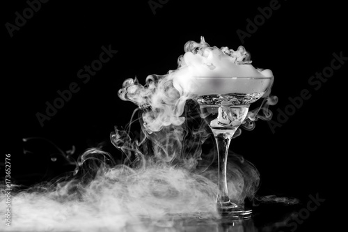 Closeup wine glass with fog at dark background. Chemical reaction of dry ice with water.