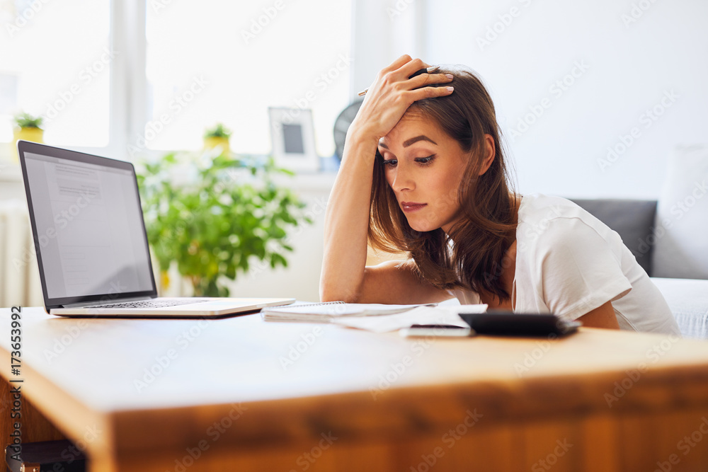 Tired student struggling to keep studying looking at notes and laptop Tired student struggling to keep studying looking at notes and laptop
