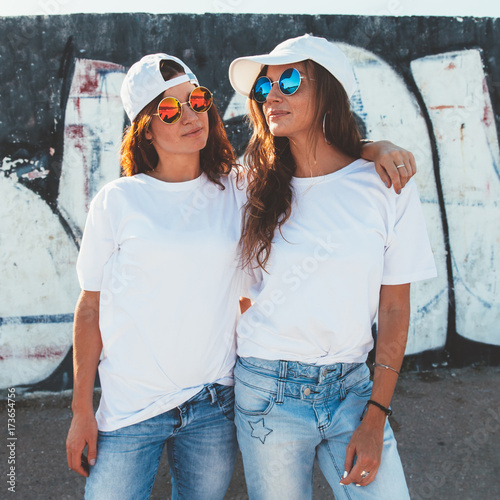 Models wearing plain tshirt and sunglasses posing over street wall