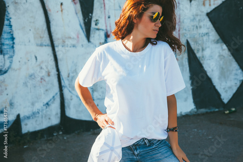 Obraz na plátně Model wearing plain tshirt and sunglasses posing over street wall