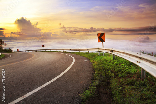 Curve road sign on down hill and clouds in the morning