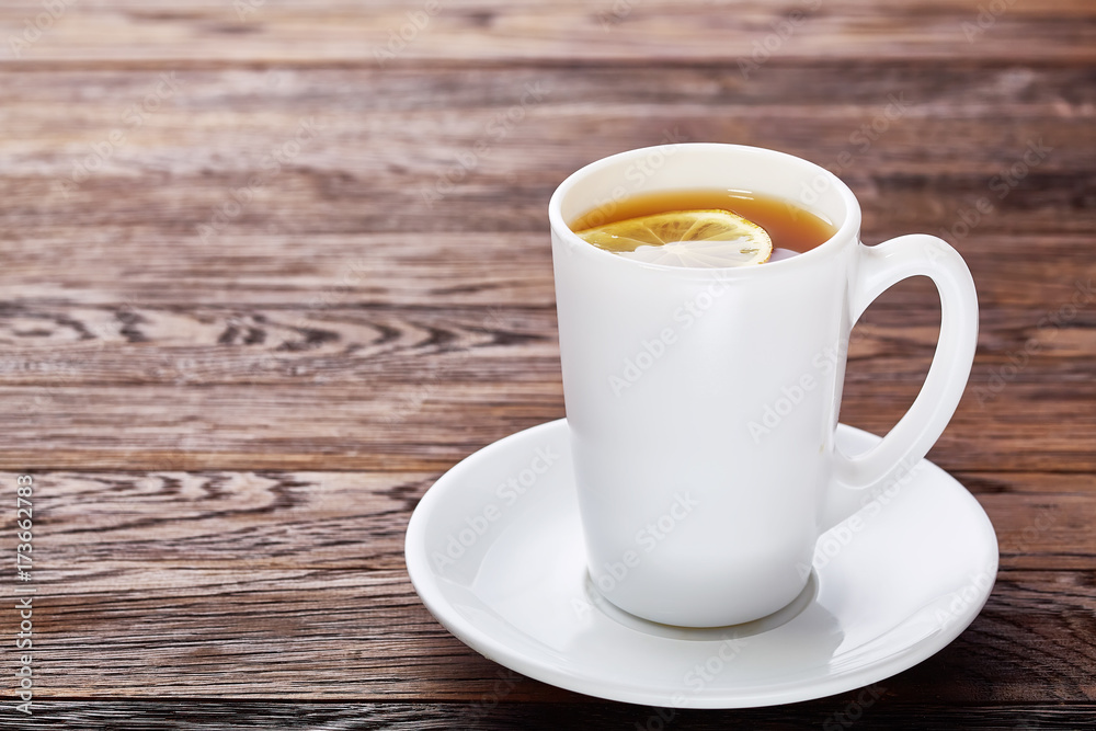 Cup with green tea and teapot on wooden background