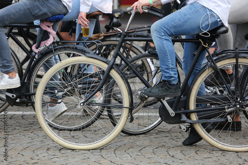 boy with blue jeans pedal on a black bicycle with many other bik
