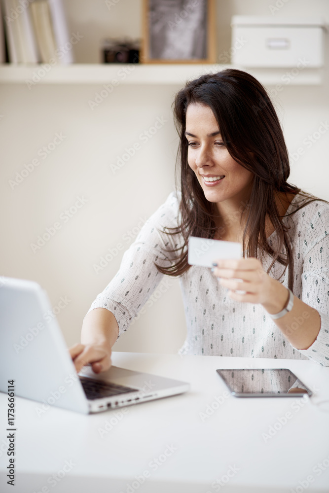 Businesswoman using laptop computer for paying bills online at home office/ self employ woman in thirties Businesswoman using laptop computer for paying bills online at home office/ self employ woman in thirties