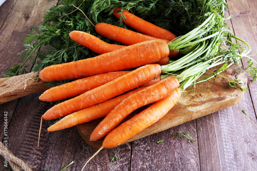 Fresh organic carrots with green leaves on wooden background. Vegetables. Healthy food