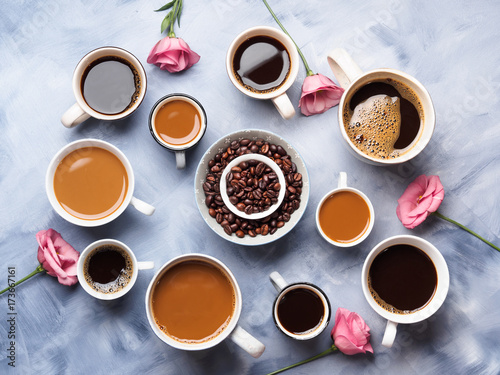 Cups and mugs of coffee and flowers on blue background