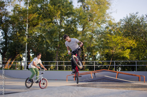 Group of young people with bmx bikes in skate plaza, stunt bicycle riders in skatepark 