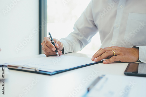 Signing a car insurance policy, the agent is holding the document © MIND AND I