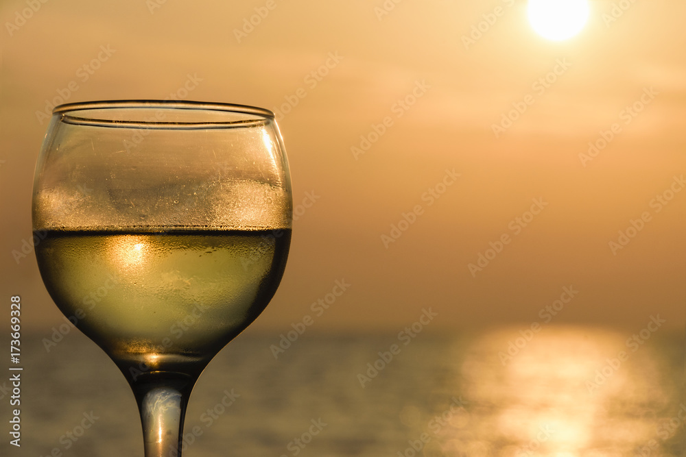 Side Angle View Of Glass Filled With White Wine Against Sea During Sunset