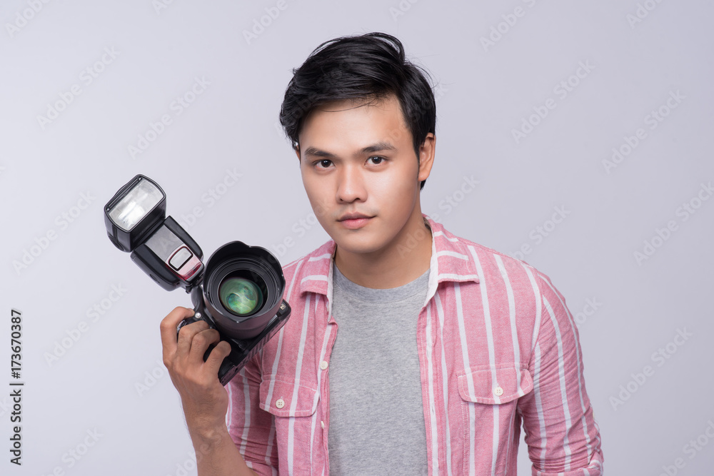 Fototapeta premium Young asian photographer holding digital camera, while working in studio