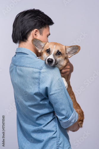 A man snuggling and hugging his dog, close friendship loving in studio background