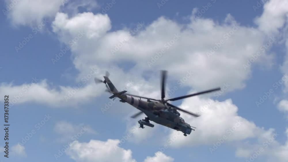 Military Helicopter Flies On The Blue Sky With White Clouds. Military Engineering of the Union of Soviets or countries of the post-Soviet space, for example, Russia Military Helicopter Flies On The Blue Sky With White Clouds. Military Engineering of the Union of Soviets or countries of the post-Soviet space, for example, Russia