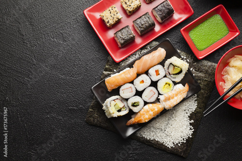 Sushi set on red and black dishes and black table background