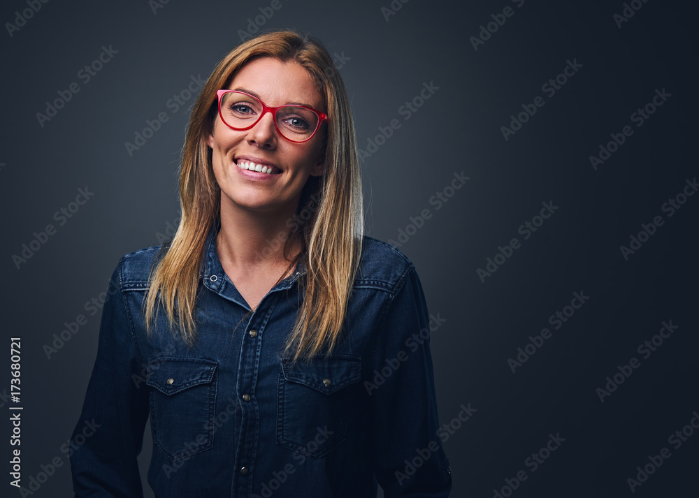 Blond female dressed in denim shirt and red eyeglasses. Blond female dressed in denim shirt and red eyeglasses.