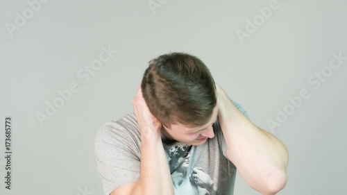 young, angry, unhappy, stressed man covering his ears, to say, stop making loud noise it's giving headache, white background