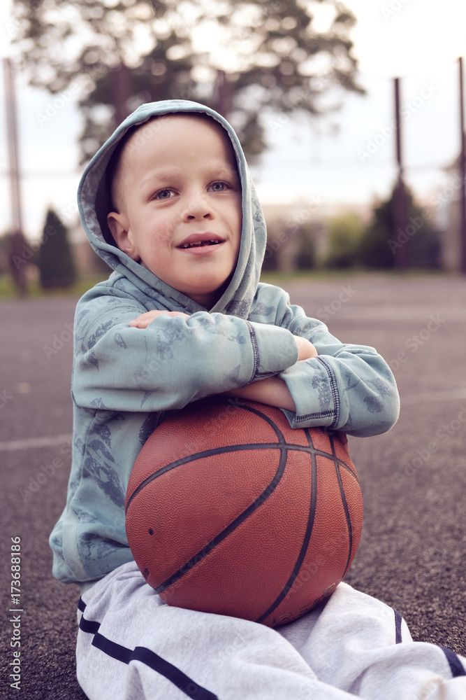 kid sitting with basketball ball on basketball street field, toned kid sitting with basketball ball on basketball street field, toned