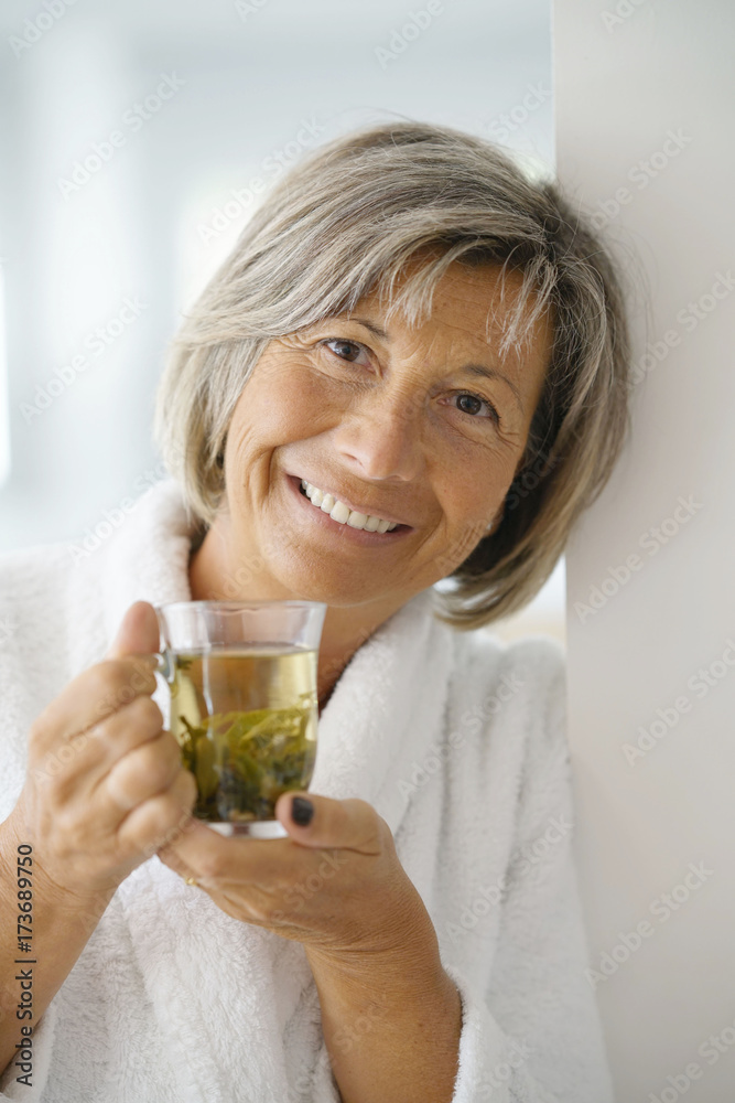 Senior woman in bathrobe drinking hot green tea Senior woman in bathrobe drinking hot green tea