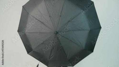 Young woman openes black umbrella on white background, slow motion photo
