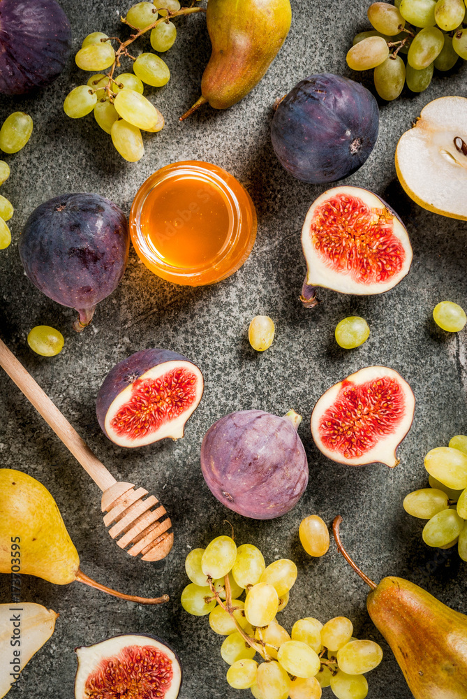 Snacks, dietary vegan desserts. Autumn fruits (figs, pears, grapes) with honey on a black stone table. Copy space top  view