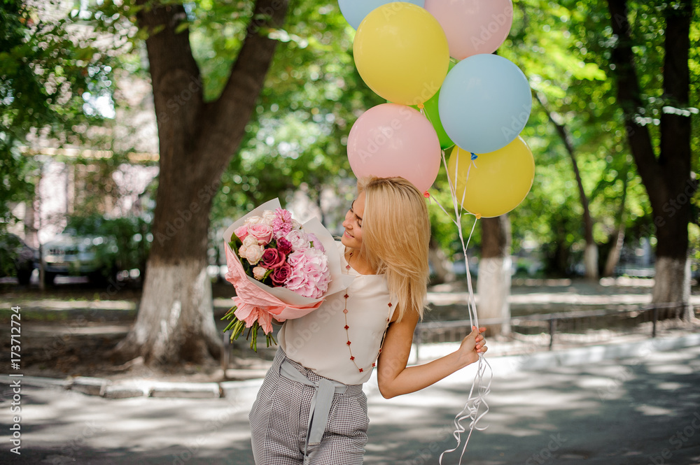 Fototapeta premium Birthday girl holding a bouquet of flowers and balloons