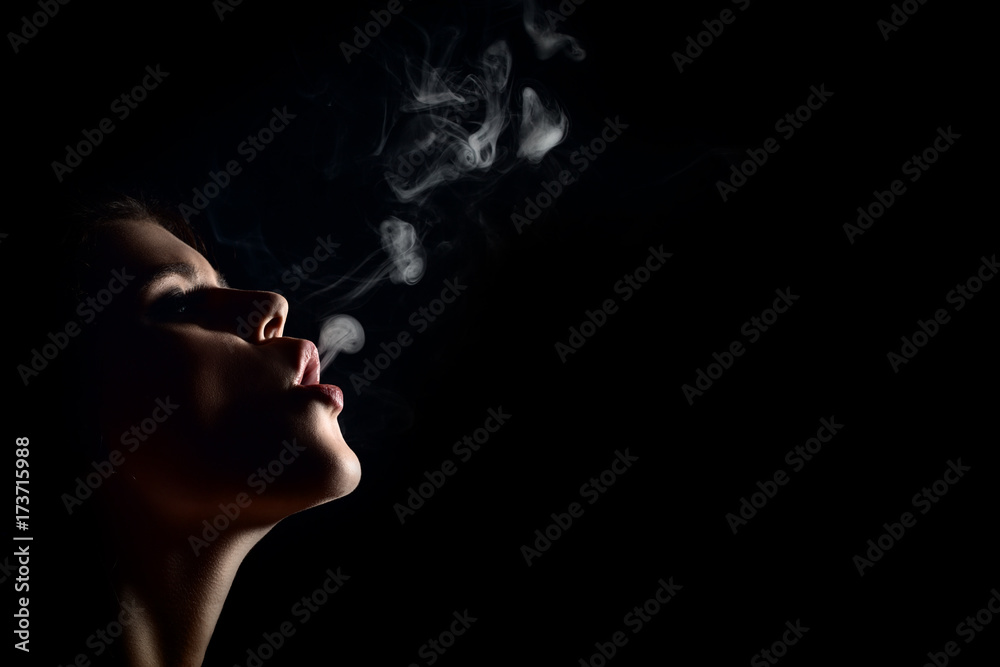 Fototapeta premium beautiful young woman smoking on black background with copy space