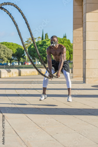 male muscular training with battle ropes and training mask photo