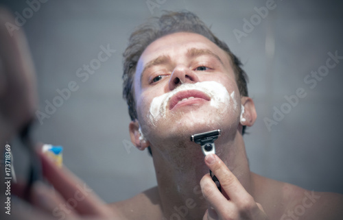 Man shaving in front of mirror in the morning