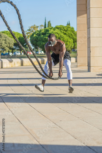 male muscular training with battle ropes and training mask photo