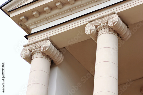 Top part of a newly restored old beige building with columns in classical style photo
